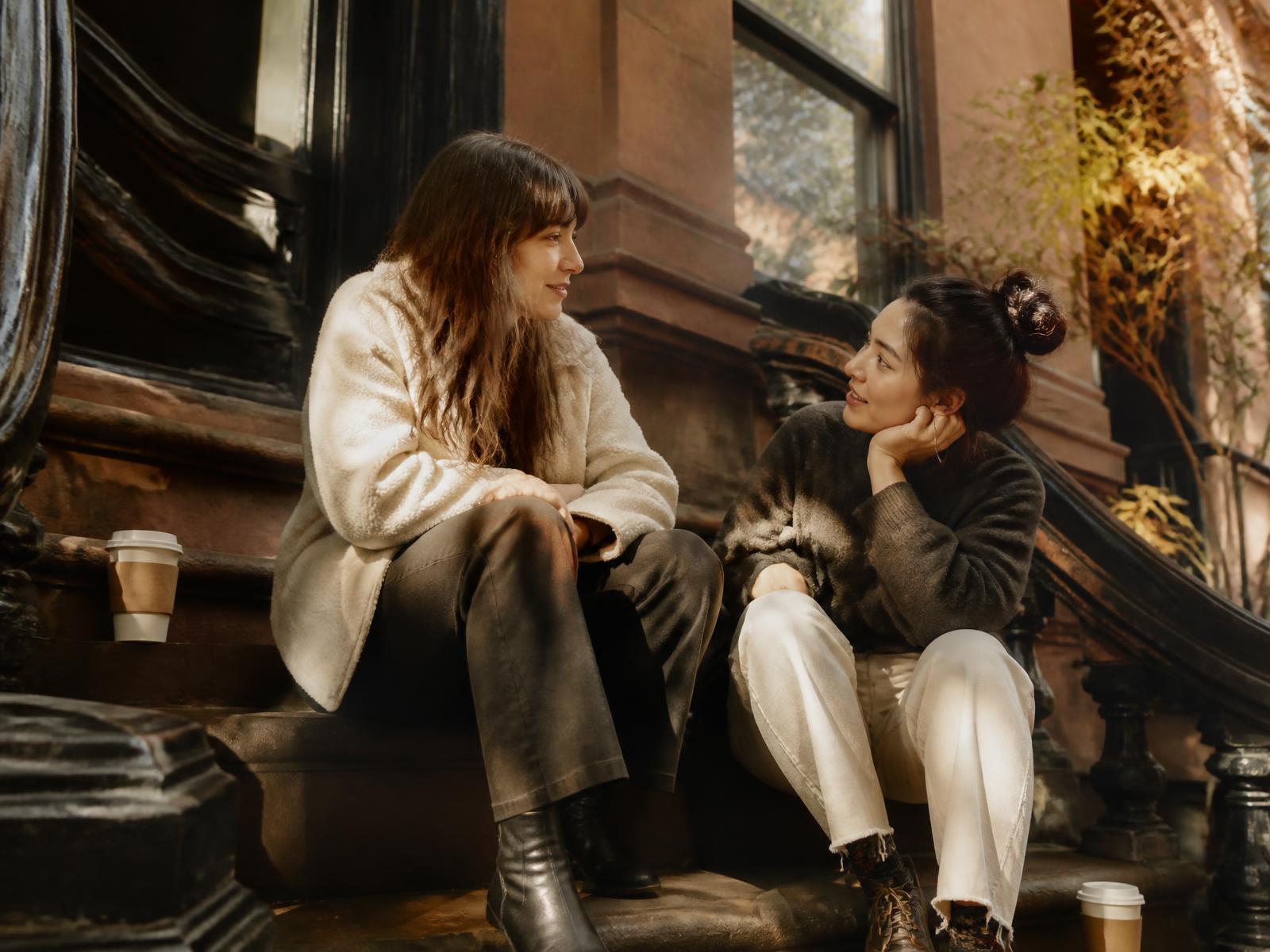 Two female friends talking on a Brooklyn stoop in late afternoon light